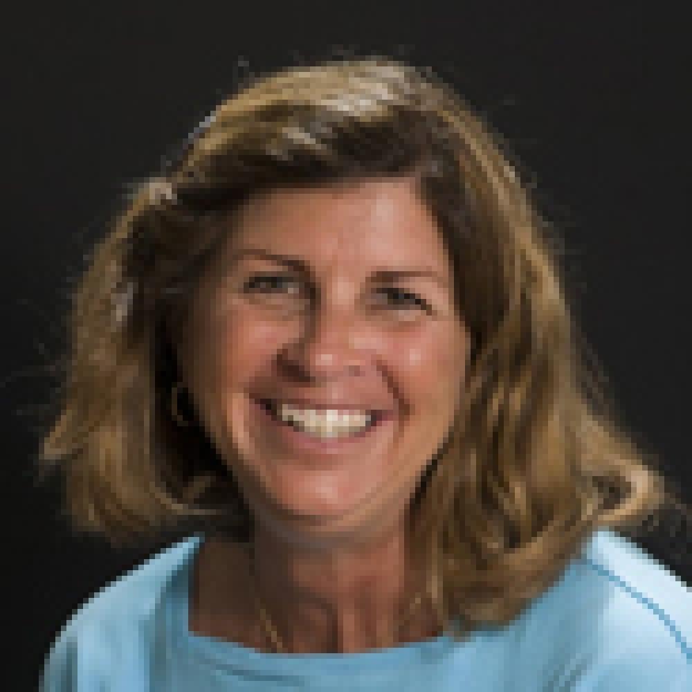 lady with wavy brunette hair wearing light blue top in front of black background