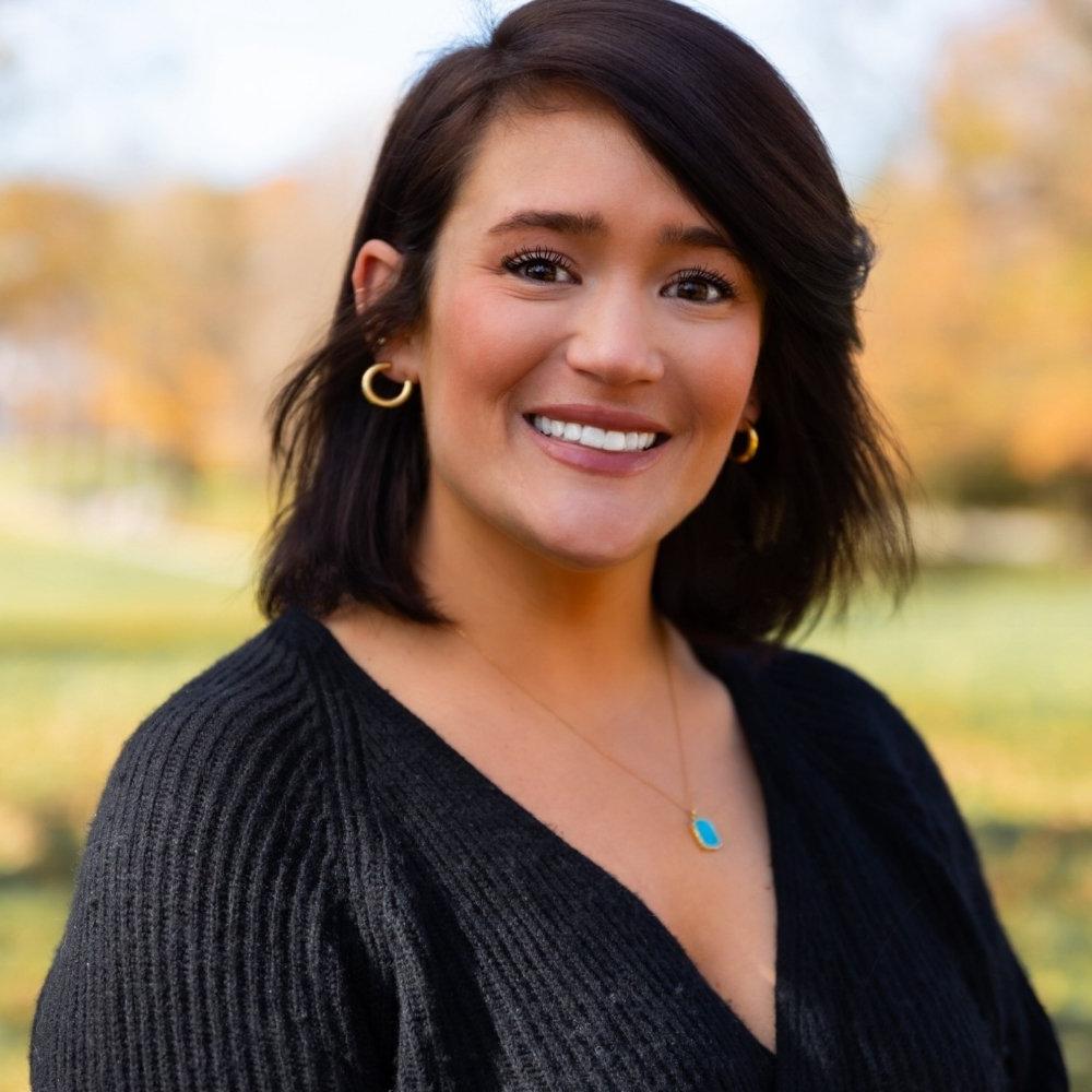 Woman with dark hair wearing a black sweater and necklace